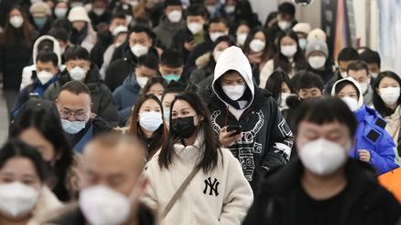 Menschen mit Mund-Nasen-Schutz gehen während der Hauptverkehrszeit durch eine U-Bahn-Station.