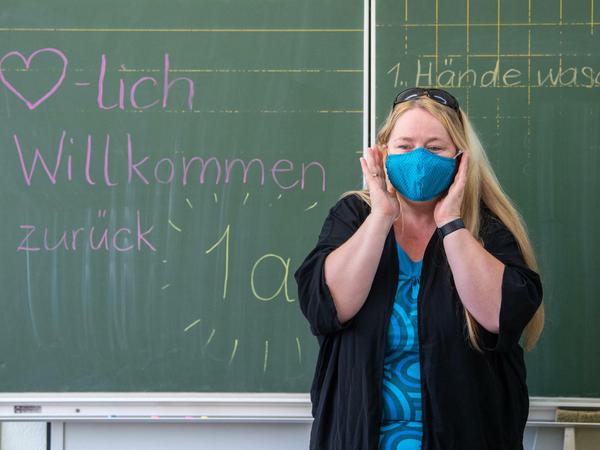 Die Lehrerin einer ersten Grundschulklasse in Sachsen erklärt ihren Schülern, wie man eine Mund-Nasen-Schutzmaske richtig anlegt und trägt.