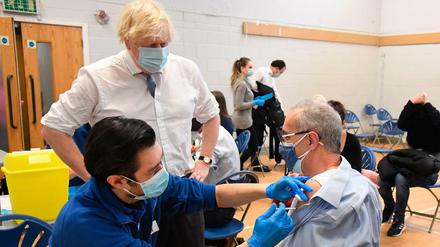 Boris Johnson (2.v.l), Premierminister von Großbritannien, beobachtet eine Booster-Impfung