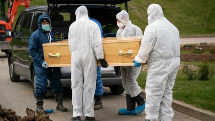 Sargträger in Schutzanzügen bringen am 03.04.2020 einen mit dem Coronaviurs infizierten Toten zu einem Leichenwagen in britischen Chislehurst.