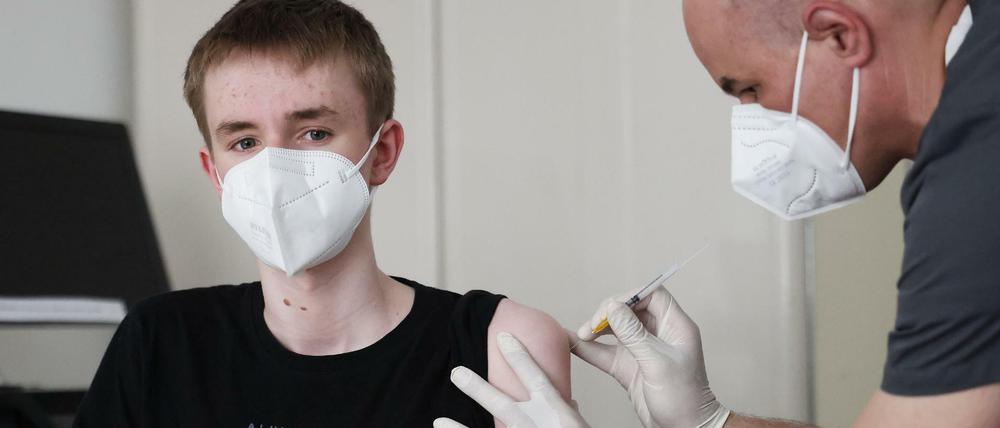 Ein Junge wird in einer Arztpraxis gegen das Coronavirus geimpft.