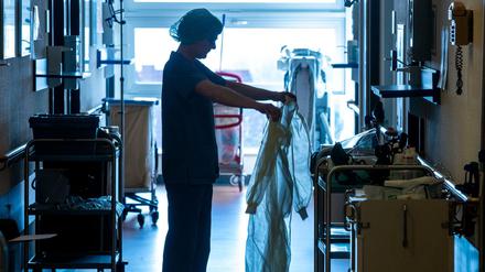 Eine Krankenschwester legt auf der Isolierstation für Coronavirus-Behandlungen einer Klinik Schutzkleidung an, bevor sie ein Patientenzimmer betritt.