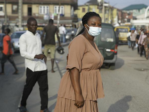 Eine Frau mit Mund-Nasen-Schutz überquert die Hauptstraße in Lagos.