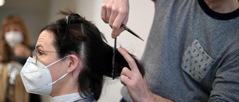 Ein Friseur schneidet einer Kundin in seinem Salon die Haare