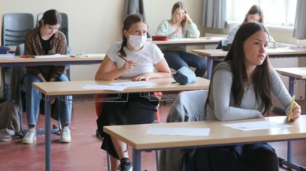 Schülerinnen einer 12. Klasse sitzen an Einzeltischen, eine von ihnen trägt einen Mundschutz.