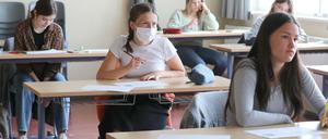 Schülerinnen einer 12. Klasse sitzen an Einzeltischen, eine von ihnen trägt einen Mundschutz.