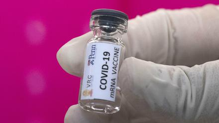 Ein Labortechniker hält einen Glasbehälter eines sich in der Entwicklung befindlichen, möglichen Covid-19-Impfstoffs in der Hand.