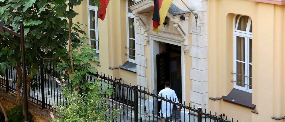Ein Mann betritt ein Gebäude, über dessen Portal eine türkische und eine deutsche Flagge zu sehen sind.