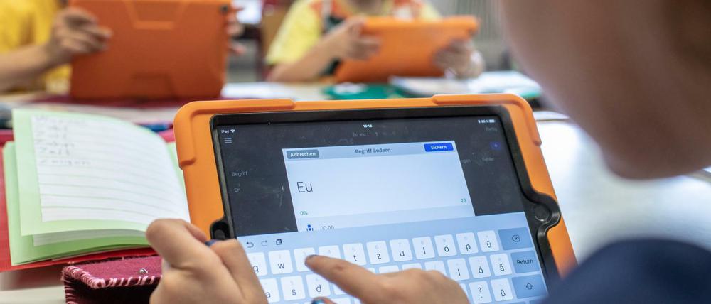 Grundschülerinnen und -schüler machen Schreibübungen auf Tabletcomputern.