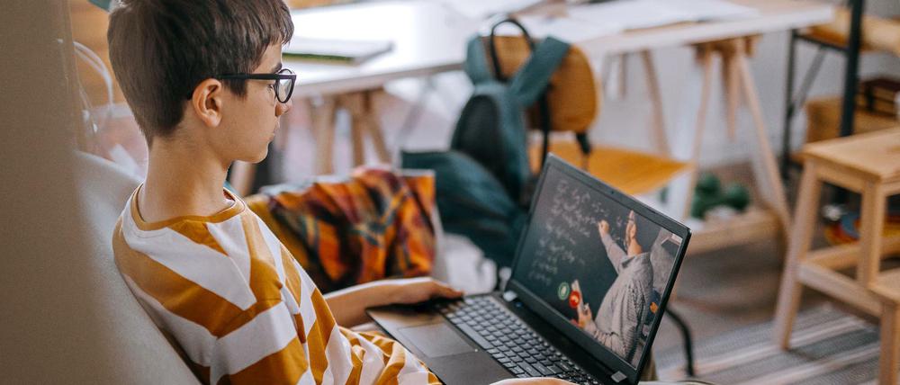 Ein Jugendlicher verfolgt den Unterricht auf einem Laptop zu Hause.
