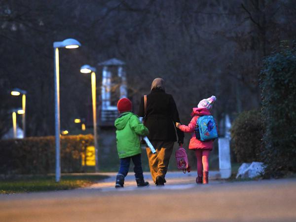 Eine Frau, die Kopftuch trägt, holt in am späten Nachmittag ihre Kinder von der Schule ab.