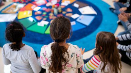 Schulkinder verschiedener Herkunft sitzen bei einem Gruppenspiel im Kreis.
