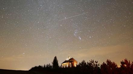 Sternschnuppen sind am nächtlichen Himmel zu sehen. Die Meteoriten gehören zu den Geminiden die alljährlich am Nachthimmel zu beobachten sind.