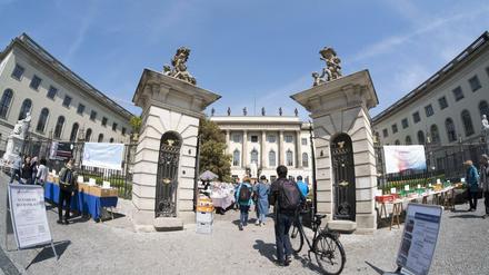 Studierende, einer davon mit dem Fahrrad, gehen durch das Eingangsportal der Humboldt-Universität Unter den Linden.