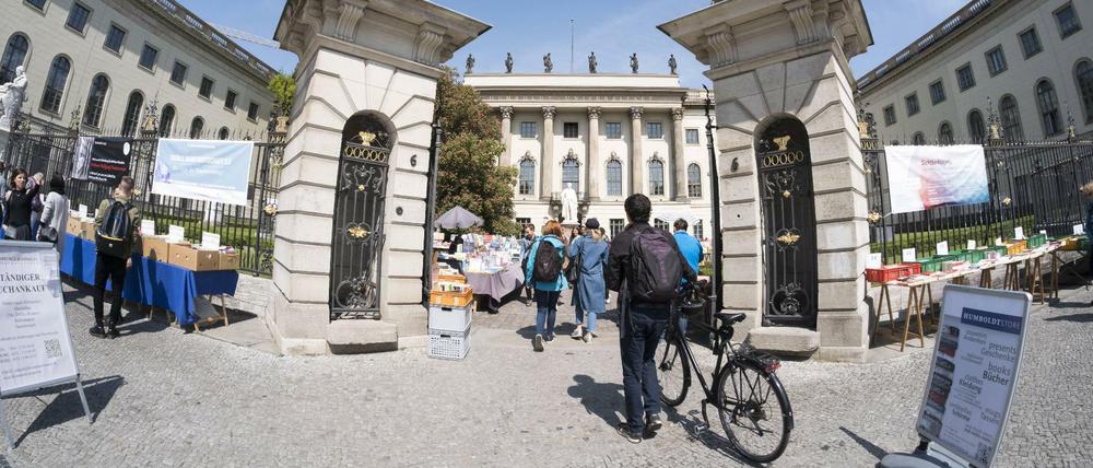 Studierende, einer davon mit dem Fahrrad, gehen durch das Eingangsportal der Humboldt-Universität Unter den Linden.