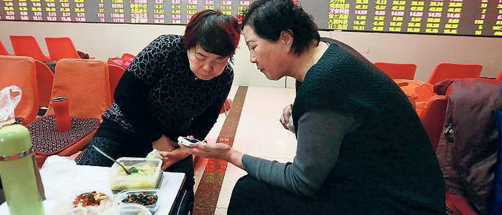 Kleines Geschäft am Rande. Zwei Investoren checken die Kurse am Smartphone in einem Lokal in Shenyang. 