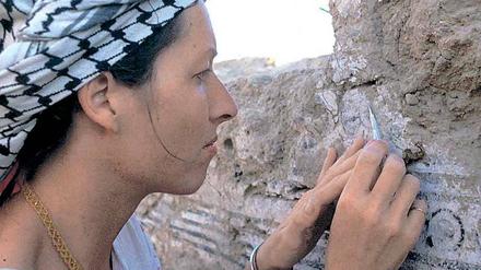 Eine Restauratorin bei der Freilegung einer in Freskotechnik bemalten Wand einer Elitenresidenz aus dem 7. Jh. v. Chr.