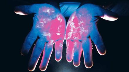 Die Spur der Keime. Unter speziellem Licht werden potenzielle Krankheitserreger auf den Händen sichtbar. Bessere Hygiene und regelmäßige Desinfektion helfen, die Übertragung von Mensch zu Mensch einzudämmen. 
