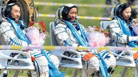 Blumen und Stühle. Die drei Taikonauten nach der erfolgreichen Landung in der Inneren Mongolei.
