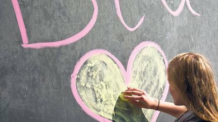 Studentin malt BTU und Herz an eine Tafel