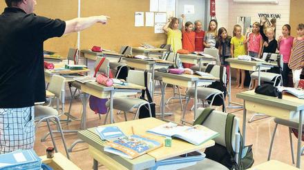 In einer finnischen Schule ruft ein Lehrer Schüler auf, die im Klassenzimmer an der hinteren Wand stehen und sich melden.