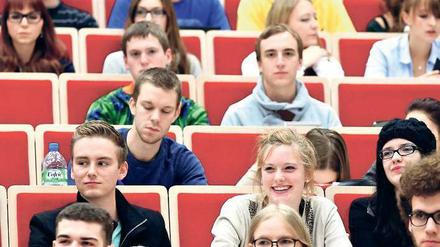 Junge Studierende sitzen lächelnd in einem Hörsaal.