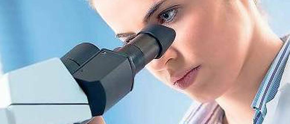 Eine junge Wissenschaftlerin im Labor, die mit einem Mikroskop arbeitet.