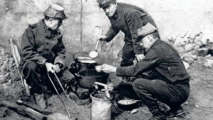 Französische Soldaten bereiten sich am Rande des Schlachtfelds eine Mahlzeit zu.