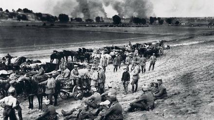 Deutsche Soldaten rasten im Jahr 1917 in Russland vor einem brennenden Dorf.