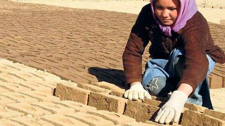 Ein Mädchen in Afghanistan arbeitet in einer Lehmziegelfabrik.