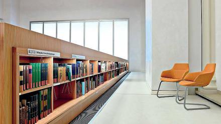 Zwei Lehre Stühle stehen in einem Bibliotheksraum auf einem leicht erhöhten Podium.