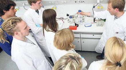 Studierende stehen in einem Labor um einen wissenschaftlichen Mitarbeiter herum.