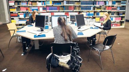 Studierende arbeiten in einer Bibliothek an Computern.