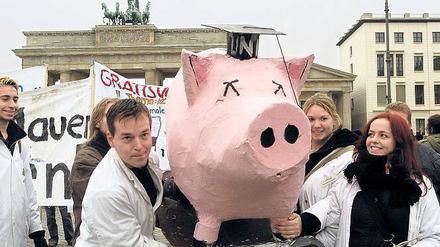 Bei einer Demonstration tragen Studierende ein Schwein aus Pappmaché.