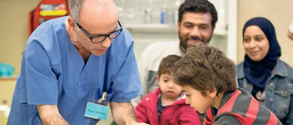 Ein Arztführt einen Kind beim Stempeln eines Impfausweises die Hand.