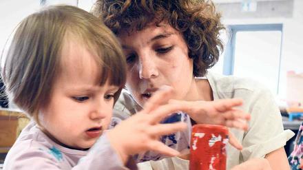 Eine junge Frau und ein kleines Mädchen kleckern Farbe auf eine Glasscheibe.