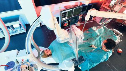 Ein Mediziner steht an einem Operationstisch, der von elektronischen Geräten umgeben ist.