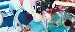 Ein Mediziner steht an einem Operationstisch, der von elektronischen Geräten umgeben ist.