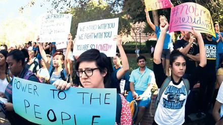 Studierende stehen auf einem Campus und halten Schilder mit Parolen doch, unter anderem ist "Not my President" zu lesen.