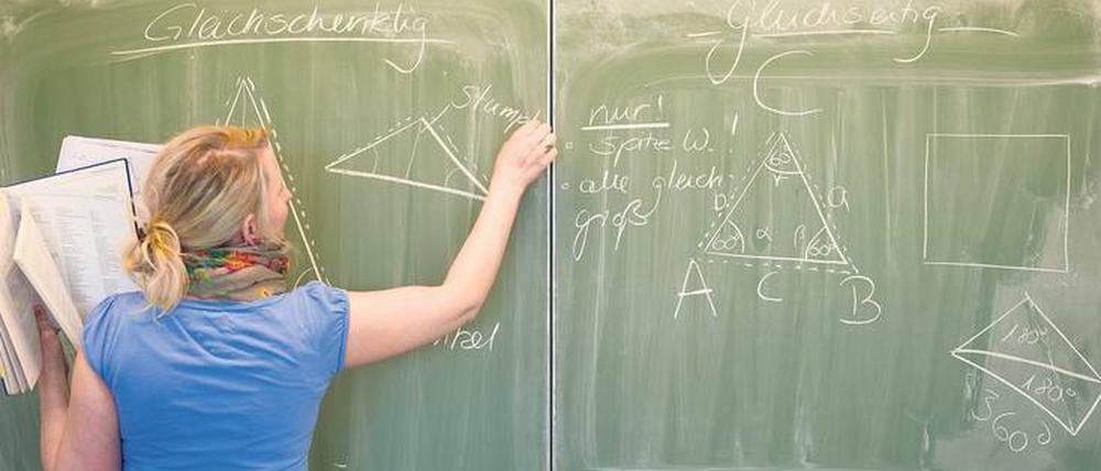 Eine Lehrerin erörtert ein mathematisches Problem an der Tafel.