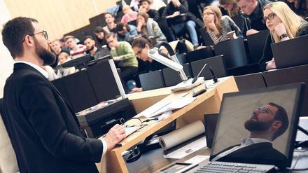 Ein junger Hochschullehrer steht in einem Hörsaal der Universität Halle vor Studierenden.