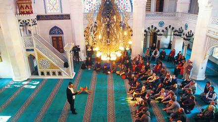 Am Tag der offenen Moscheen 2015 in der Berliner Sehitlik-Moschee spricht ein Vertreter der Moschee mit Besuchern.