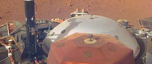 Am 26. November 2018 setzte die Nasa-Sonde „Insight“ in Äquatornähe des Roten Planeten auf. An Bord war ein Seismometer (rot), das mit einem Roboterarm neben dem Lander abgesetzt wurde und mit einer Haube vor Wind und Staub geschützt wird (weißgrau hinter dem roten Seismometer). Auch der „Maulwurf“ Berliner Forscher wurde von seinem Platz auf dem Lander (der schwarze, schmale Aufbau neben dem Schutzschild) auf den Marsboden versetzt. 