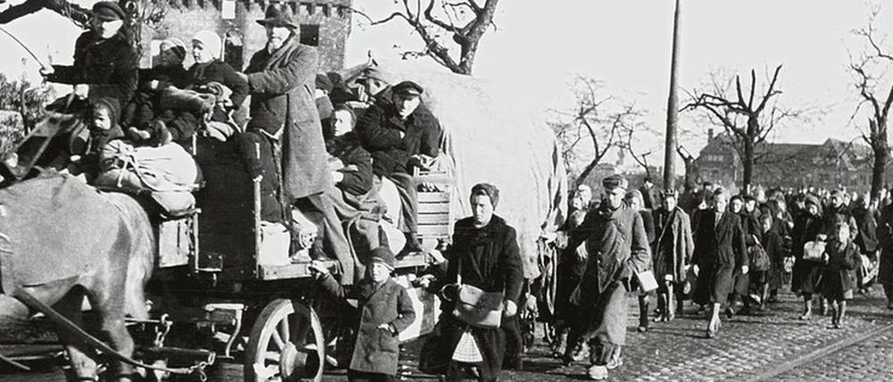 Ein Flüchtlingstreck im Jahr 1945, die Menschen gehen zu Fuß oder fahren auf einem Pferdwagen.