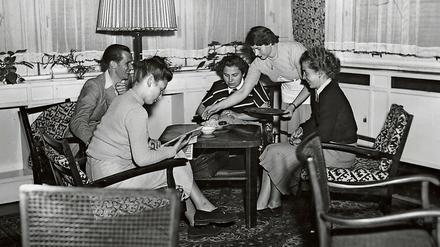 Auf einem Foto aus den frühen 1950er Jahren sitzen Studentinnen und Studenten auf Sesseln an einem Teetisch und unterhalten sich.