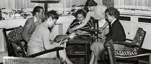 Auf einem Foto aus den frühen 1950er Jahren sitzen Studentinnen und Studenten auf Sesseln an einem Teetisch und unterhalten sich.