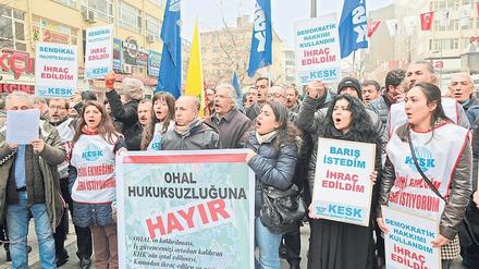 Frauen und Männer stehen mit Plakaten und Fahnen auf einem Platz in Istanbul.