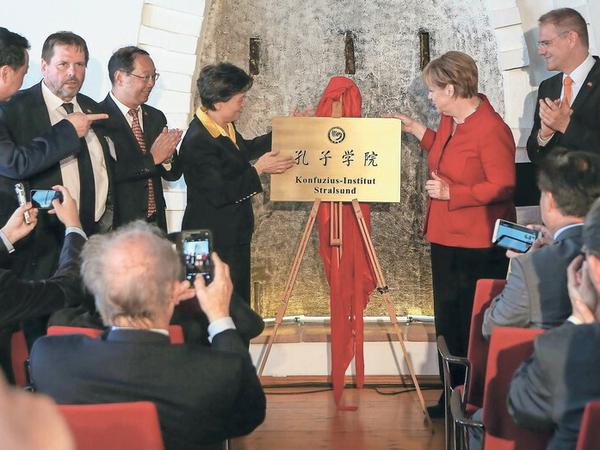Kanzlerin Merkel hat mit anderen Würdenträgern eine goldene Tafel mit den Worten Konfuzius-Institut Stralsund enthüllt.