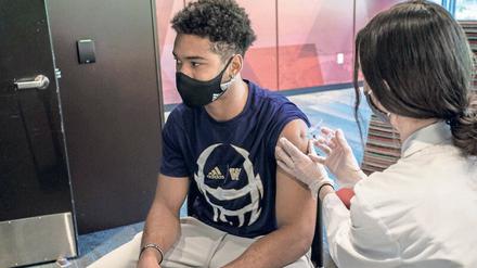 An einer US-Universität wird ein Student von einer Ärztin geimpft.