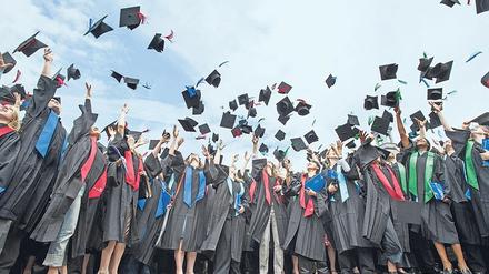 Bei einer Absolventenfeier an der Universität Bonn werfen junge Frauen und Männer ihre "Doktorhüte" in die Luft.